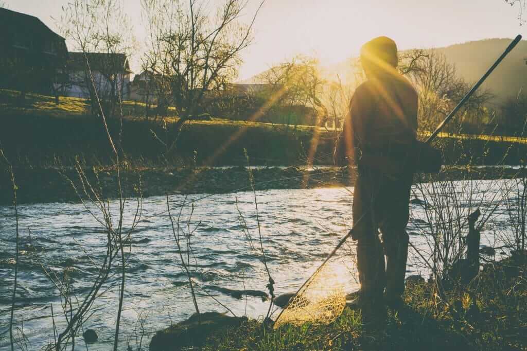 Man bass fishing a river during the fall