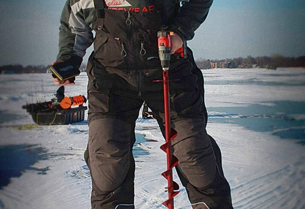 angler with an ice fishing bib and and an ice fishing auger