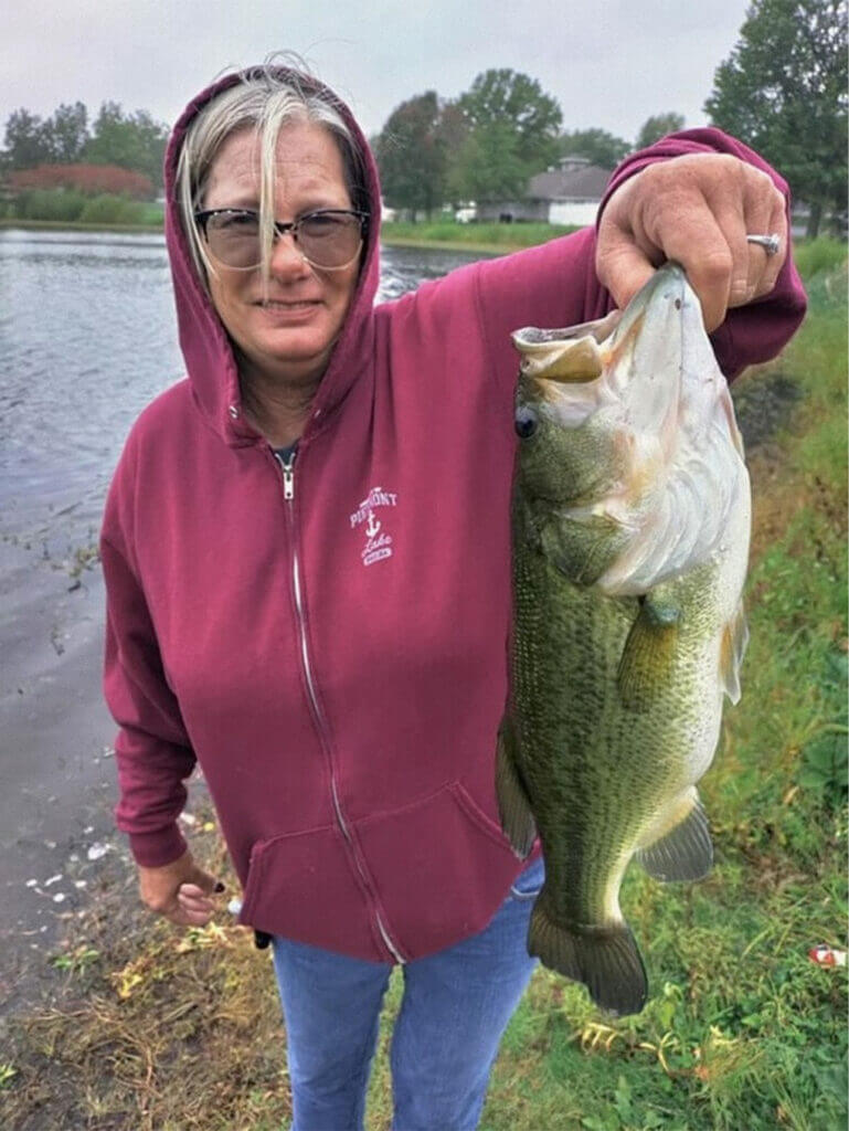 Tami Reed posed with one of the big bass she caught Tuesday on a subdivision lake in central Indiana. (photo courtesy of John Reed)